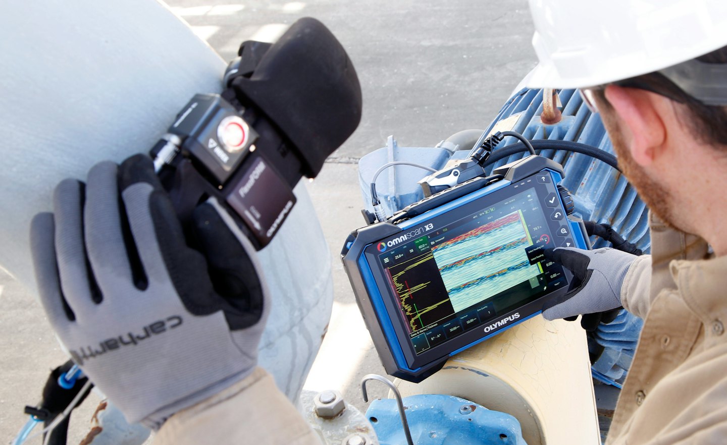 Technician uses a sensor and tablet to test an industrial pipe.