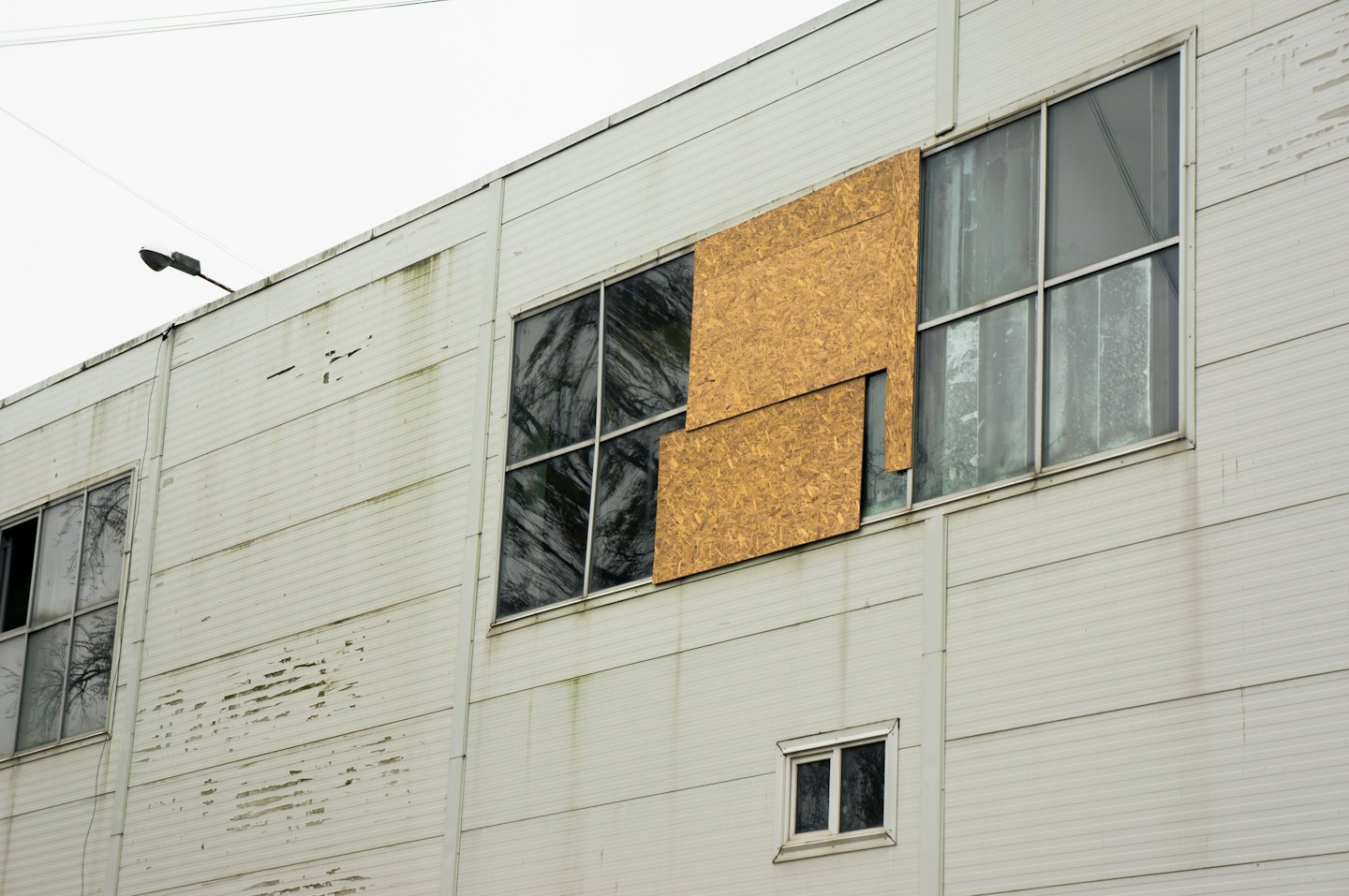 A weathered commercial building facade with a boarded window.
