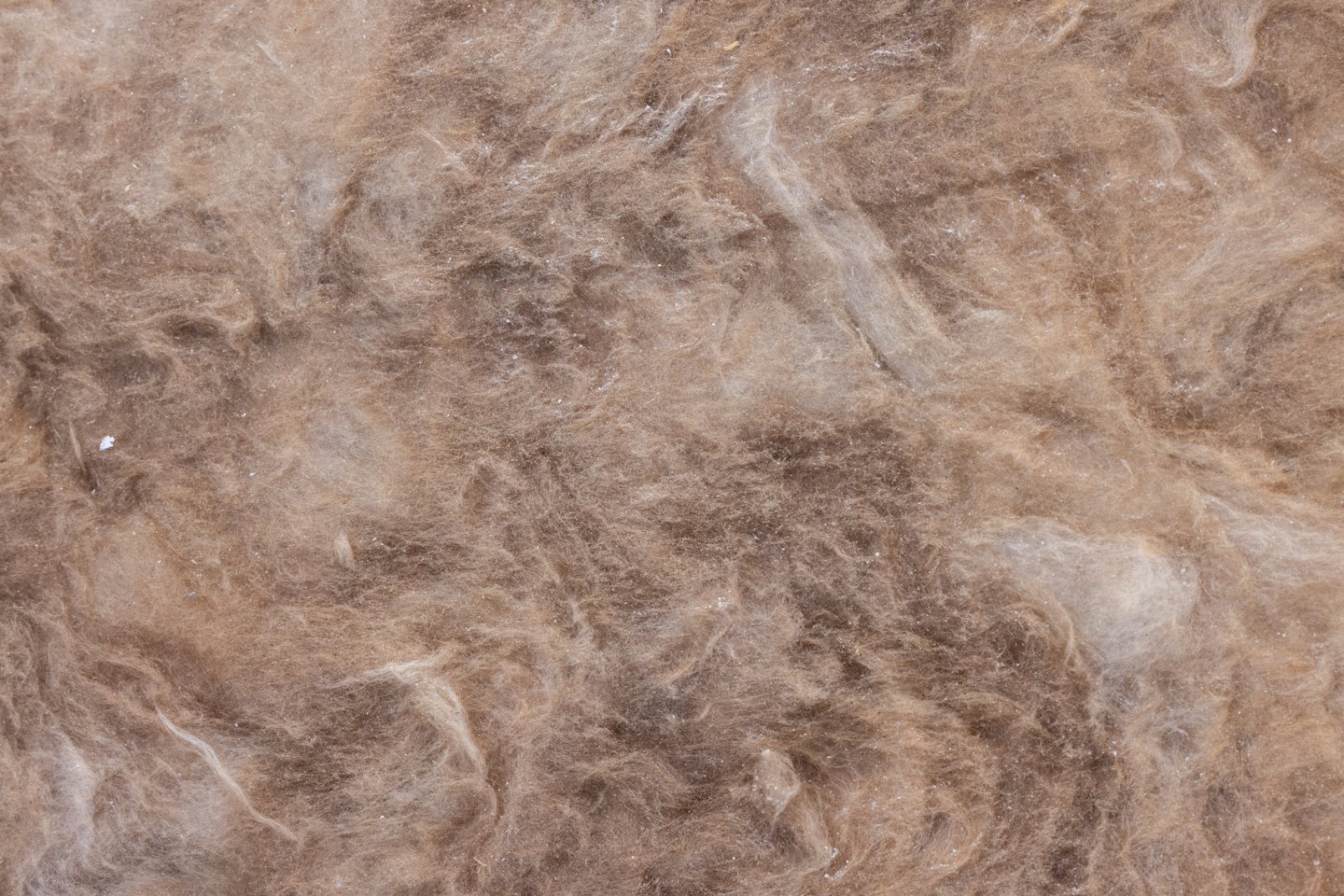 Brown and beige fibrous insulation material with tangled fibers.